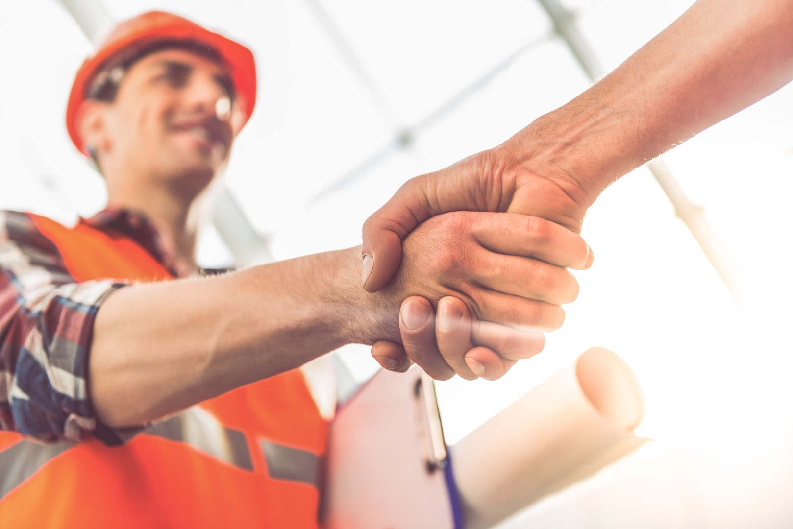 Construction worker with orange vest and hard hat shaking hands