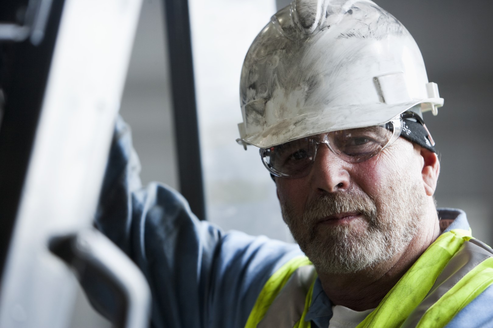 Male construction worker with a white hard hat and safety glasses